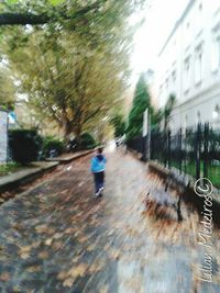 Rear view of man walking on wet road