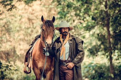 Cowboy with horse standing in forest