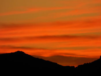 Scenic view of silhouette mountains against orange sky