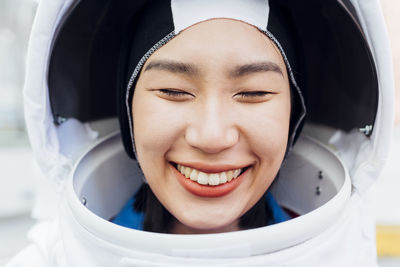 Smiling female astronaut with eyes closed wearing space helmet