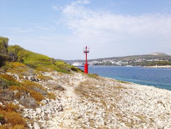 Lighthouse by sea against sky