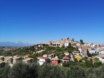 Buildings in town against clear blue sky