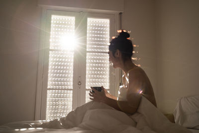 Man using mobile phone while sitting on bed at home