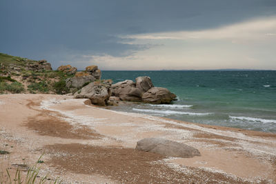 Scenic view of rocks on beach against sky