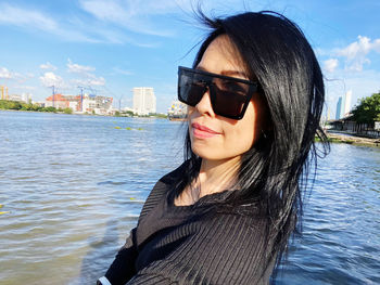 Portrait of young woman in sunglasses against sky