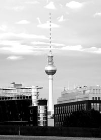 Communications tower in city against sky