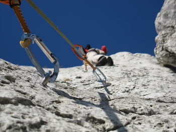 Low angle view of person rock climbing against clear sky