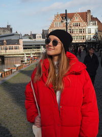 Young woman wearing sunglasses standing against city buildings