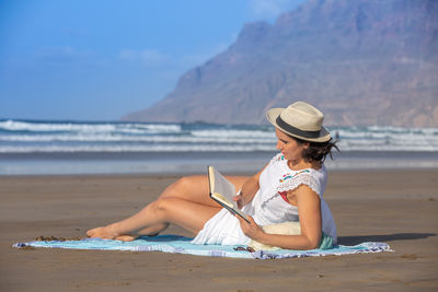 Female tourist reading interesting book on beach