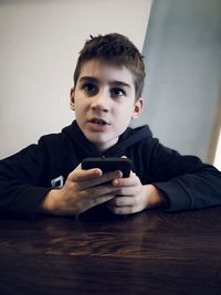 Portrait of boy holding mobile phone at home