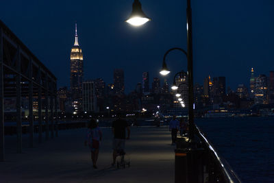 Illuminated buildings by street against sky at night