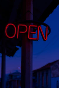 Low angle view of illuminated neon sign against sky at night