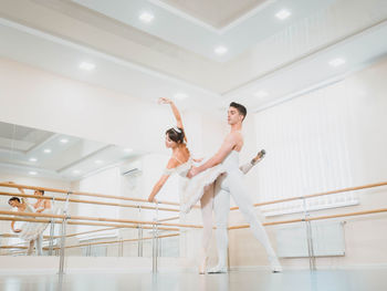 Full length of man and woman practicing ballet dance in studio
