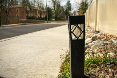 A black path light in a patch of green grass on a street in suburban pennsylvania