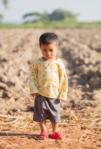 Full length of boy standing on field against sky