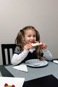Portrait of cute little girl sitting at  table, eating cake