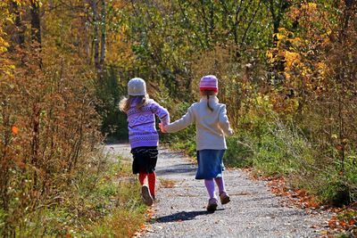 Rear view of girls running on footpath