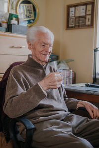 Smiling senior man drinking water at home