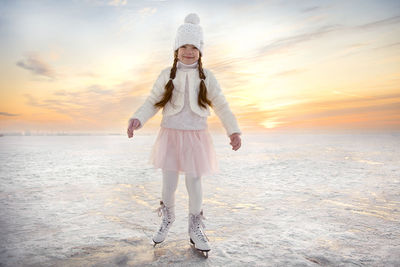 Little girl skating on ice in evening sunset light. winter sports on natural background.