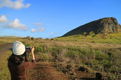 Rear view of woman photographing mountain while standing on land