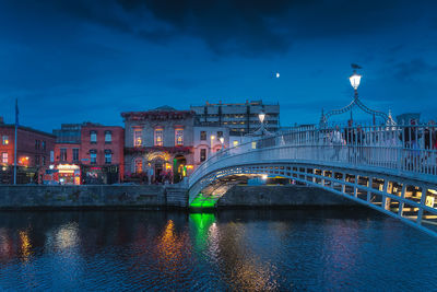 Illuminated bridge over river against sky at night