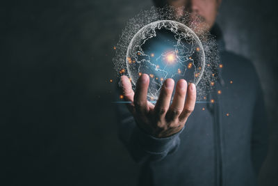 Digital composite image of hand holding ball against black background