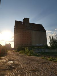 Street amidst buildings against sky during sunset