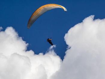 Low angle view of person paragliding against blue sky