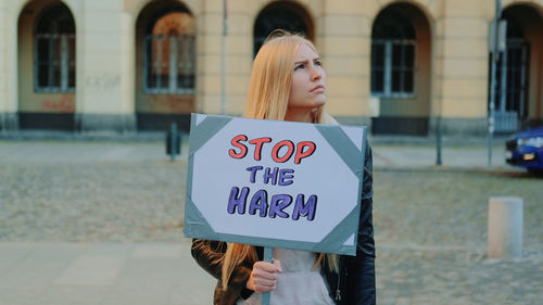 Woman with banner standing against building in city