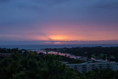 Village in city against sky during sunset