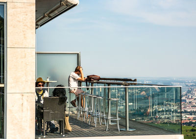 People sitting on railing against buildings