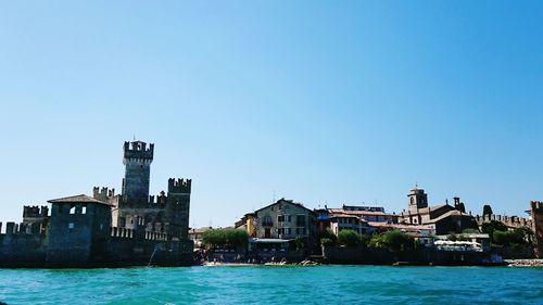 Buildings at waterfront against blue sky