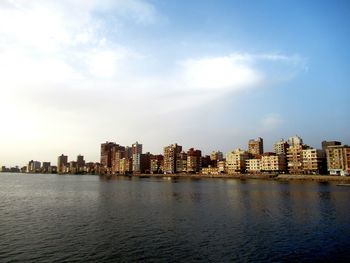 Sea by buildings against sky in city