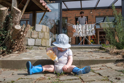 Side view of boy sitting on footpath