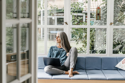 Woman sitting on lounge in winter garden with laptop