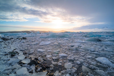 Scenic view of frozen lake against sky during sunset