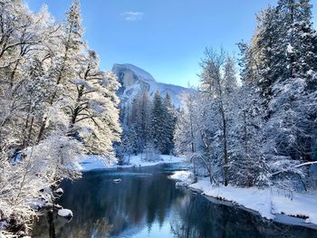 Frozen lake by snowcapped mountain against sky