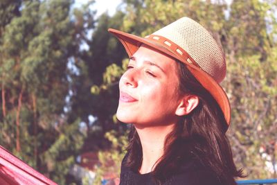 Close-up of young woman wearing hat against trees