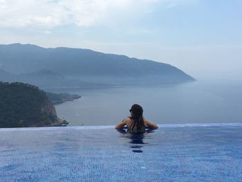 Rear view of woman in swimming pool against sky