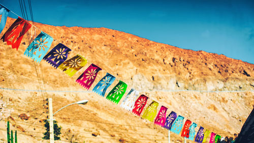 Low angle view of colorful flags against mountains on sunny day