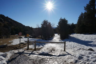 Snow covered field against sky on sunny day