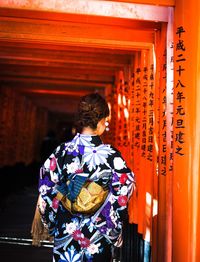 Rear view of woman walking in torri gate