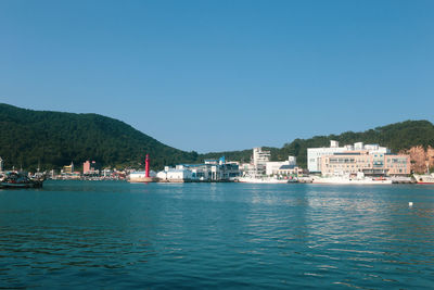 Scenic view of sea by buildings against clear blue sky