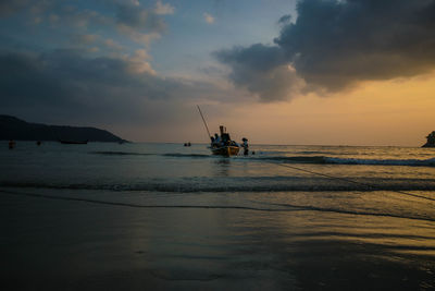 Silhouette people on sea against sky during sunset