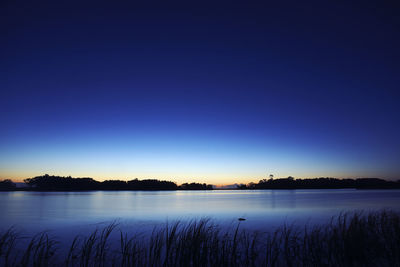Scenic view of lake against clear blue sky at night