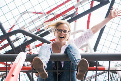 Portrait of smiling young woman sitting on railing