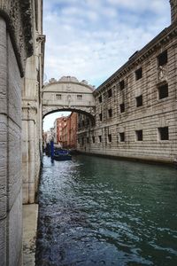 Arch bridge over canal in city against sky