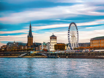 Buildings by river against sky