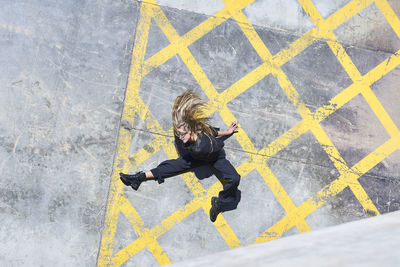 Woman tossing hair while sitting on footpath