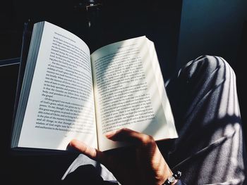 Cropped image of man reading book while sitting at home